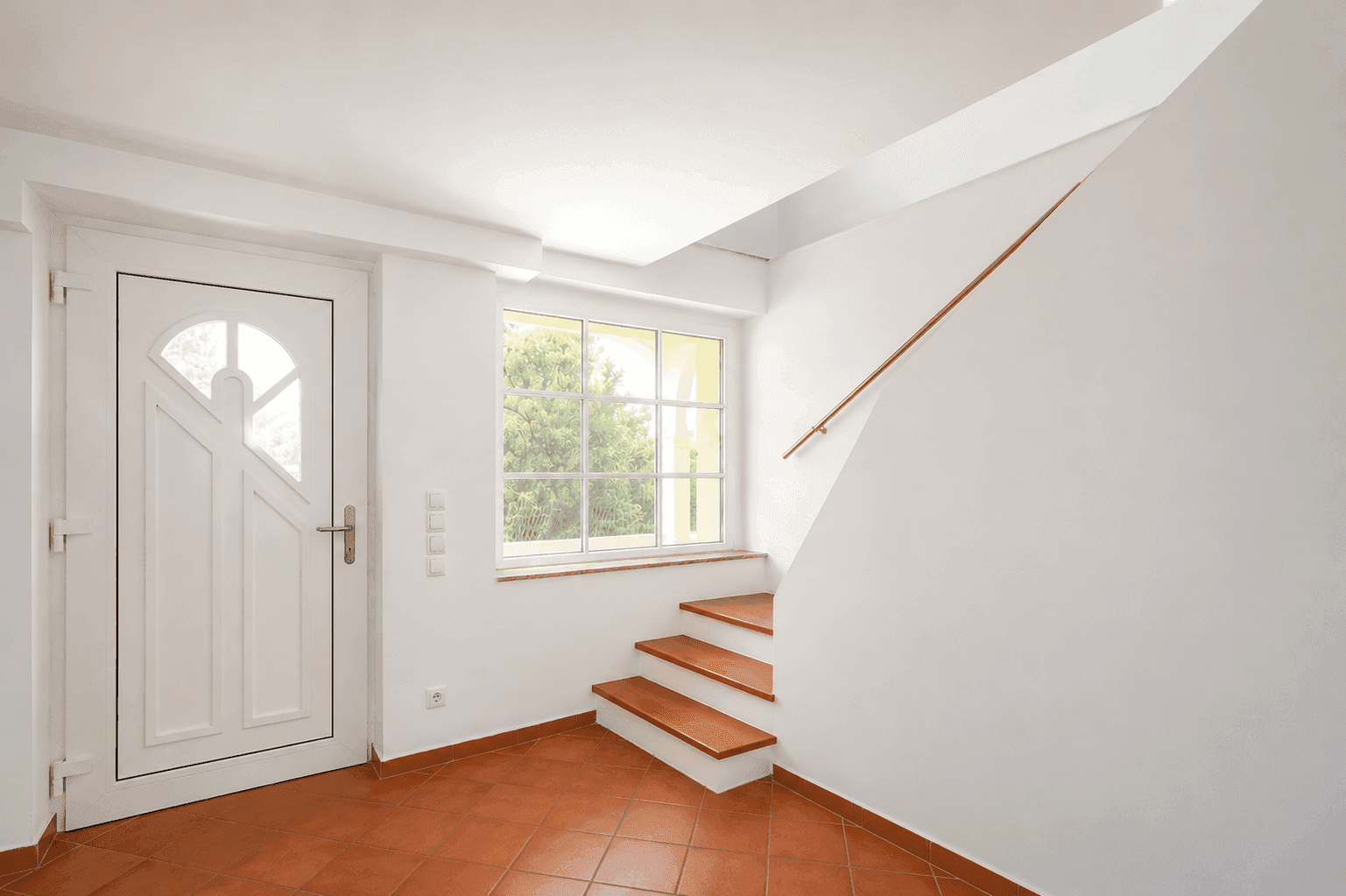 Heller Eingangsbereich mit Haustür, Treppe und Fenster, gefliest mit Terrakotta-Fliesen.