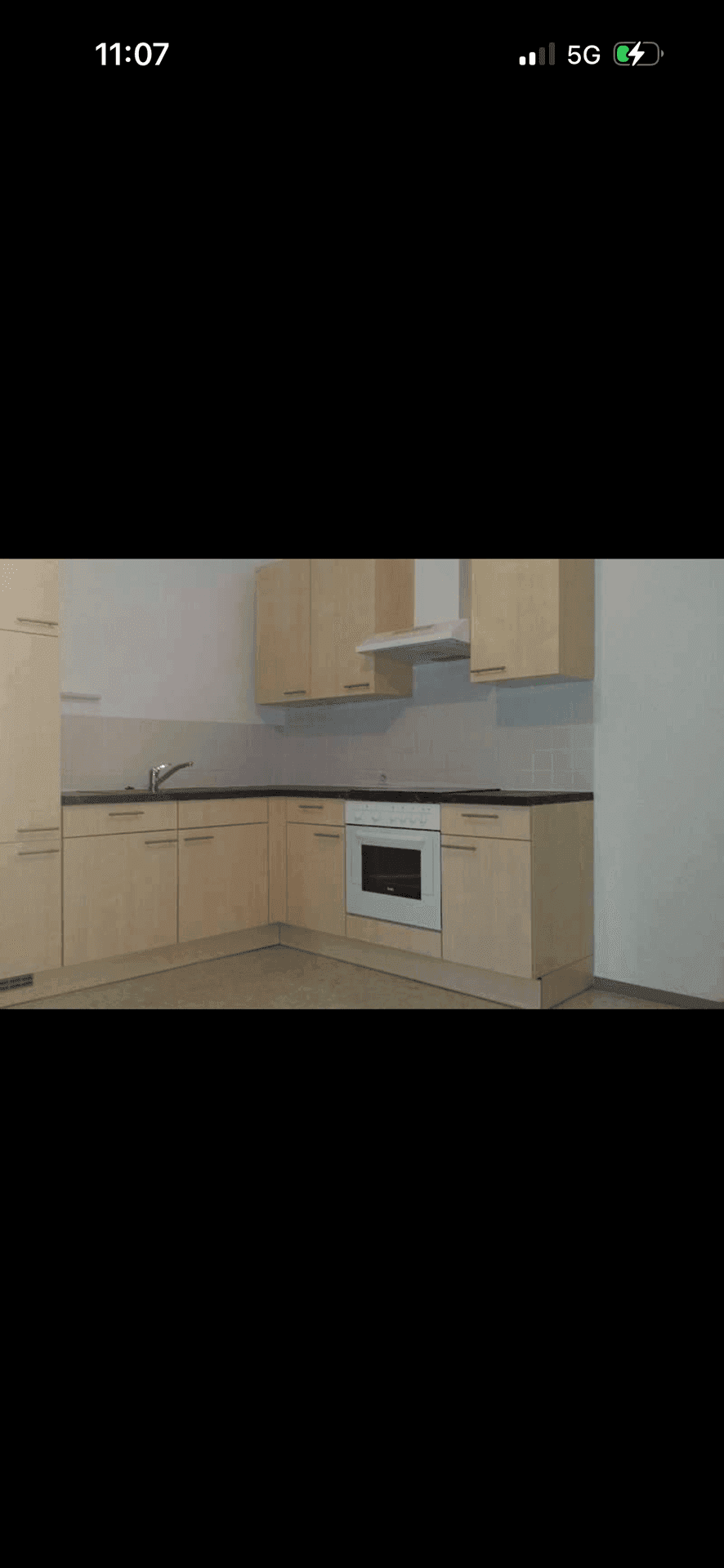 Funktionale Küche mit hellen Holzschränken, integriertem Backofen und Dunstabzugshaube.