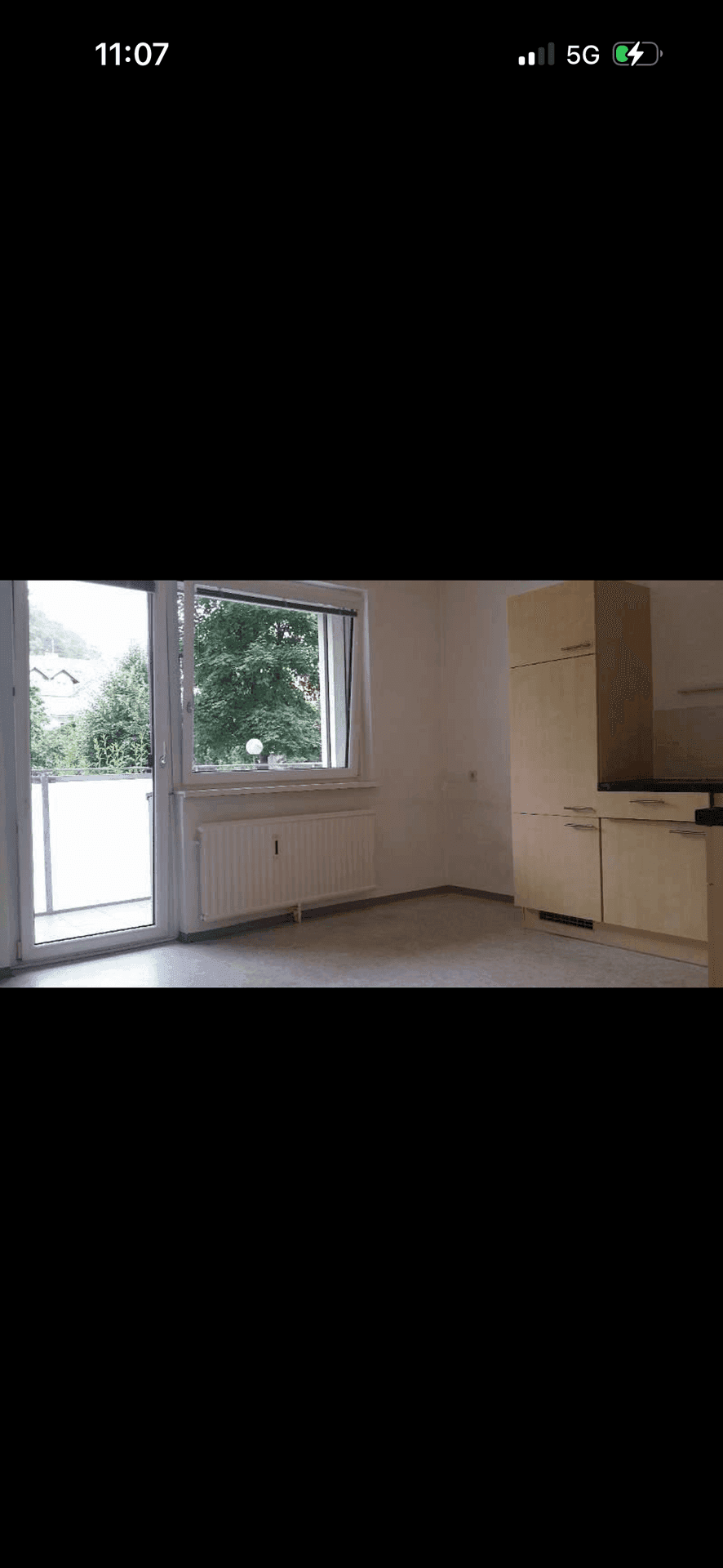 Küchenbereich mit hellen Holzschränken und Zugang zu einem Außenbereich durch eine Fenstertür.