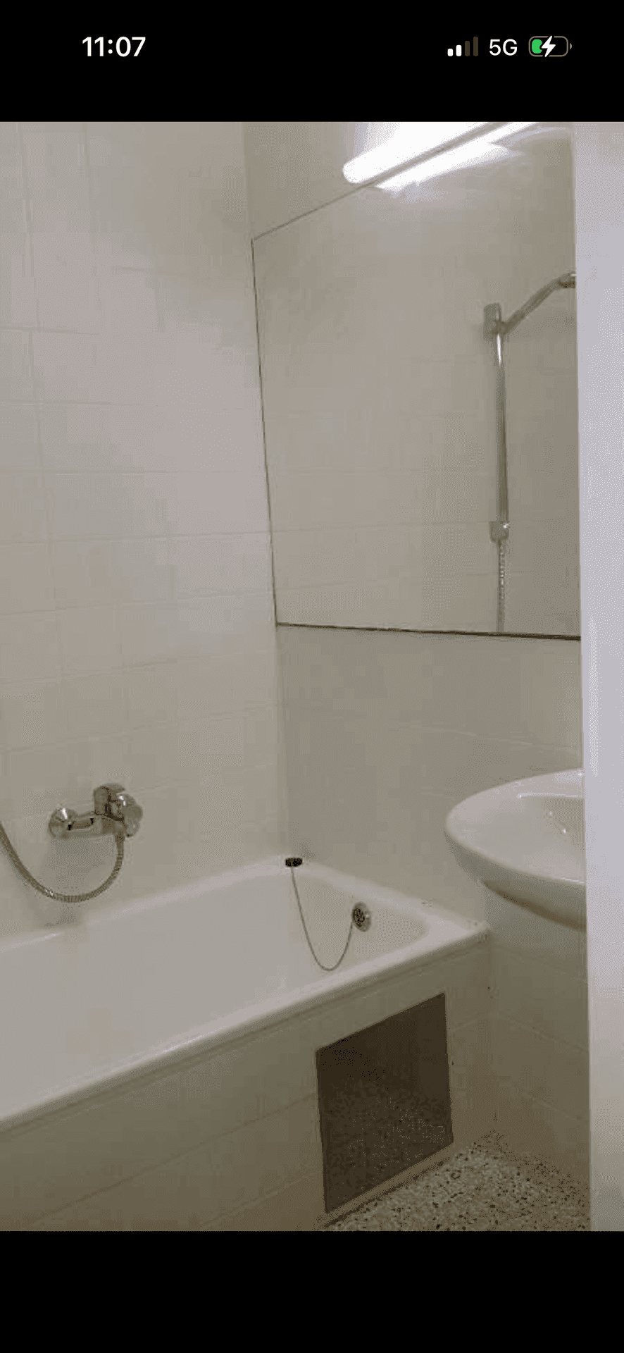 Badezimmer mit Badewanne, Duschvorrichtung, Waschbecken und großen Wandspiegeln.