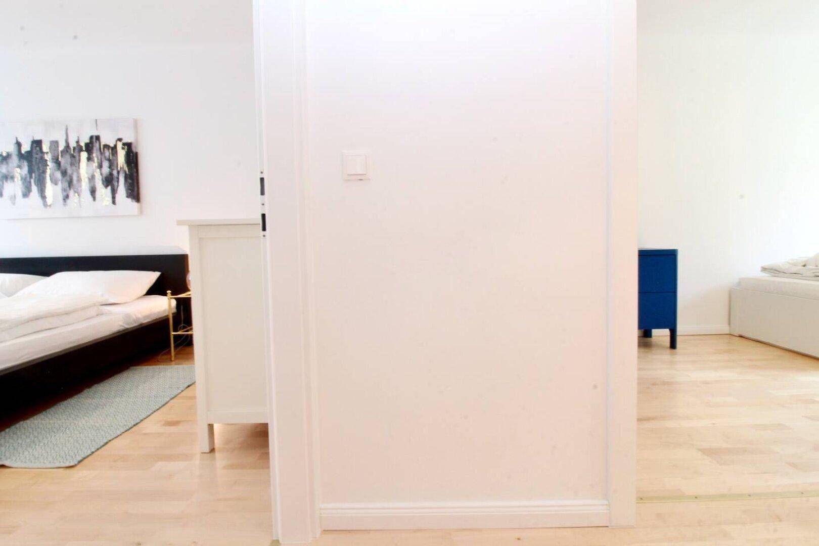 Schlafzimmer mit hellem Holzboden und minimalistischer Einrichtung.