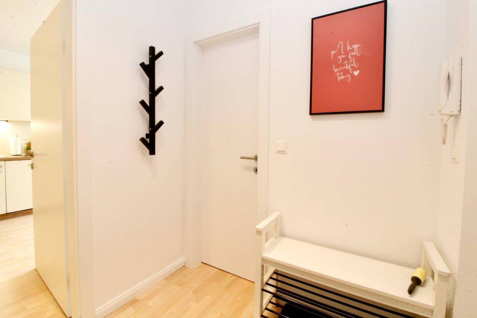 Heller Flur mit Garderobe, Schuhbank und rotem Wandbild.