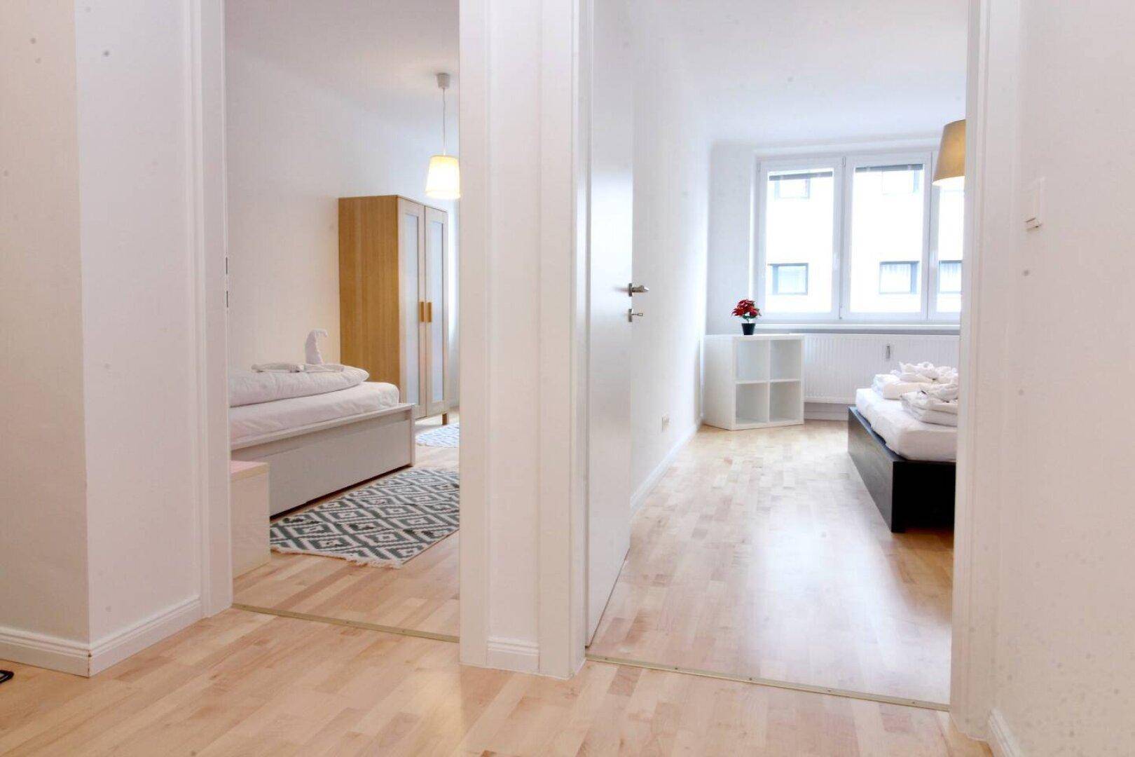 Heller Flur mit Zugang zu zwei Schlafzimmern und Holzboden.
