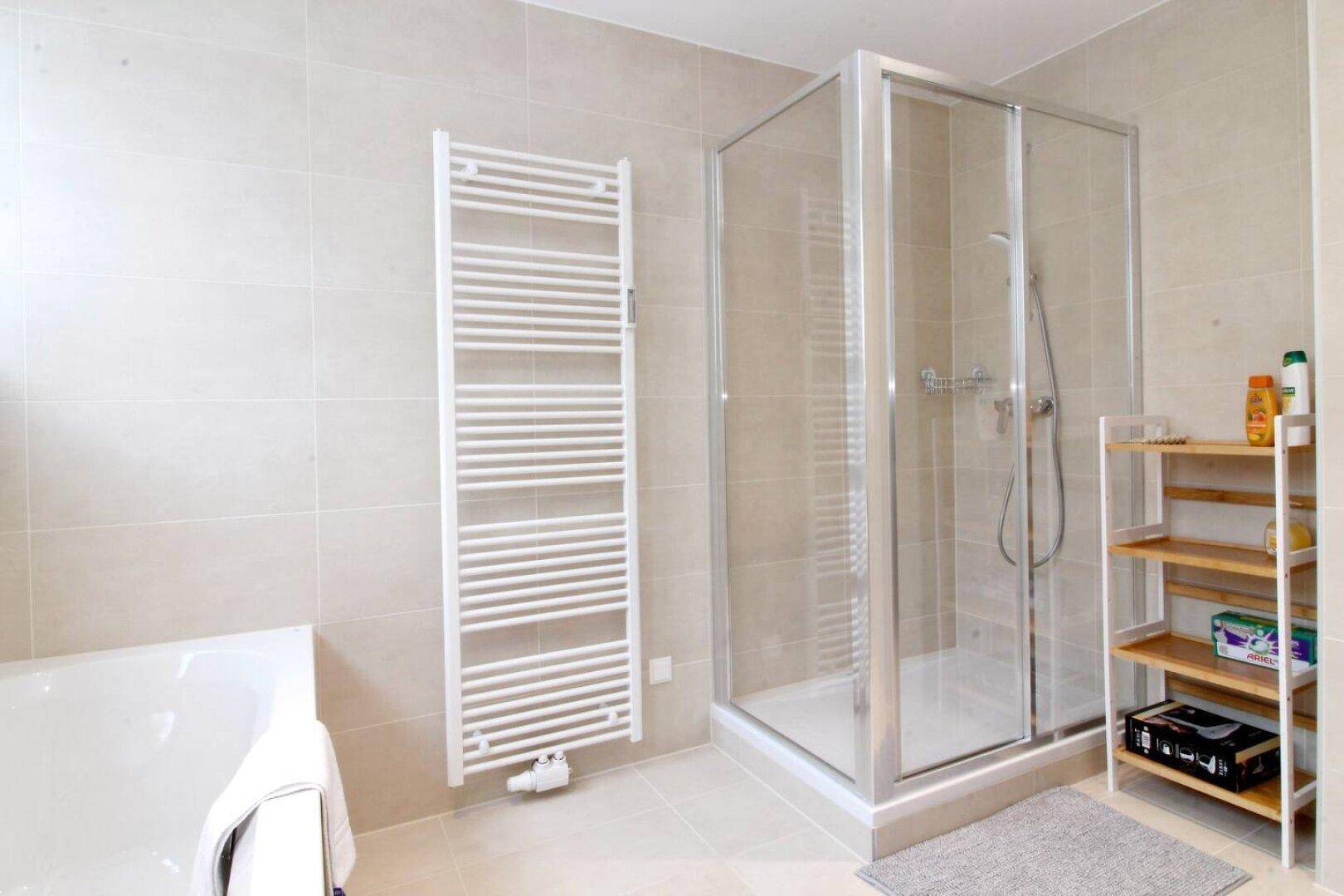 Modernes Badezimmer mit Dusche, Badewanne und beheiztem Handtuchhalter.