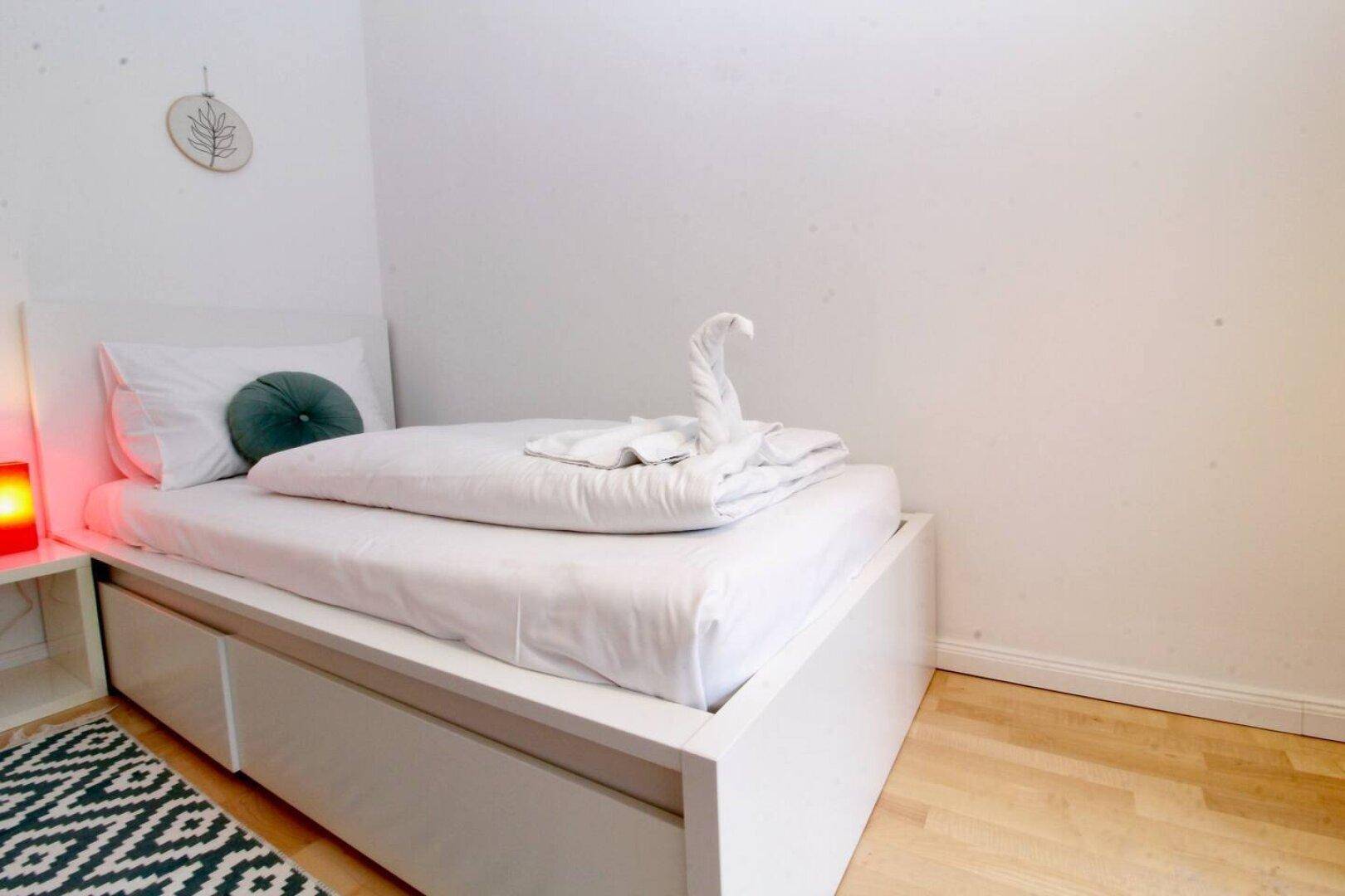 Schlafzimmer mit Einzelbett, Stauraum und modernem Teppich.