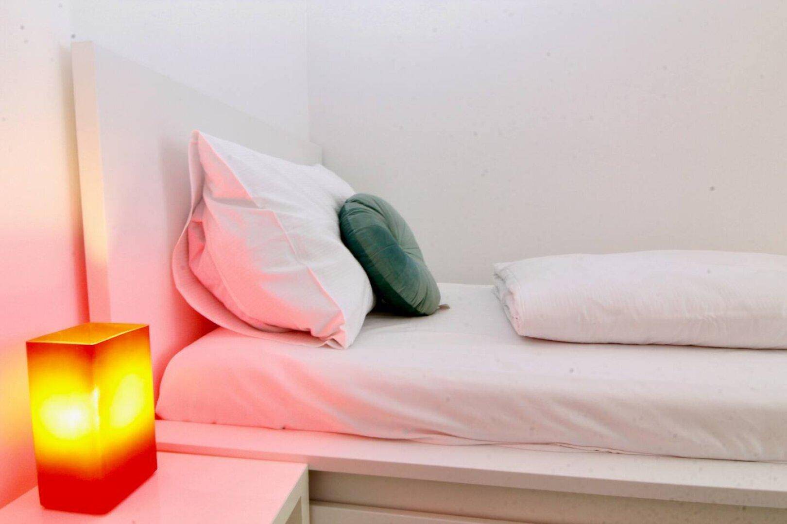 Gemütliches Schlafzimmer mit Einzelbett und Nachttischlampe.