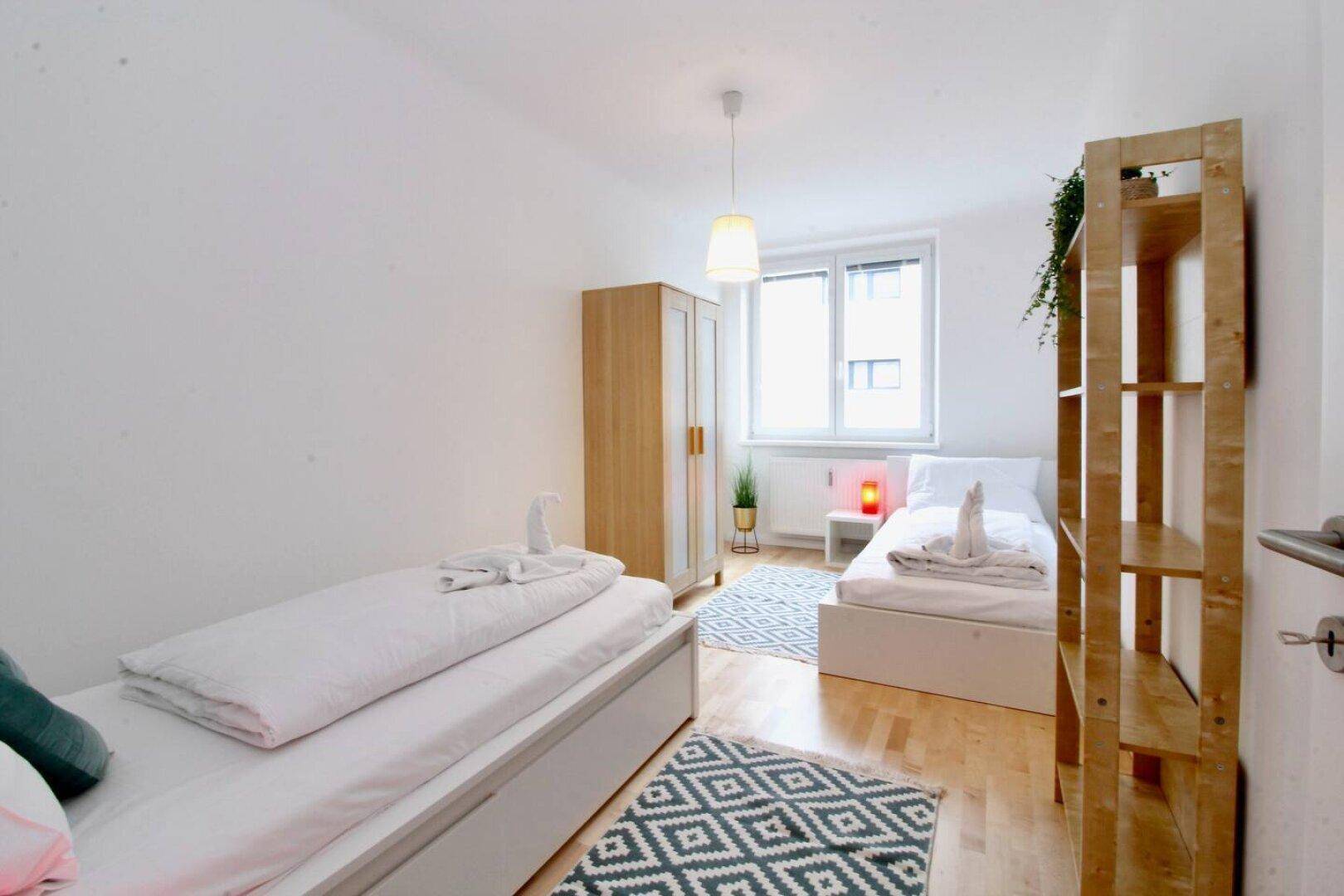 Helles Schlafzimmer mit zwei Einzelbetten, Kleiderschrank und Holzboden.
