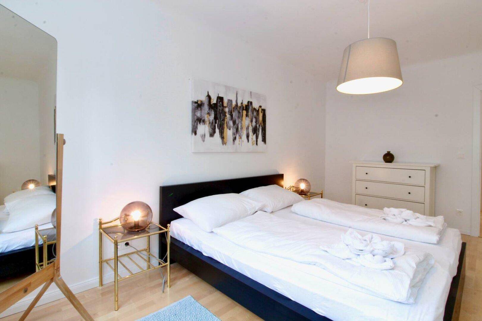 Gemütliches Schlafzimmer mit Doppelbett, stilvollen Nachttischen und einem großen Spiegel.