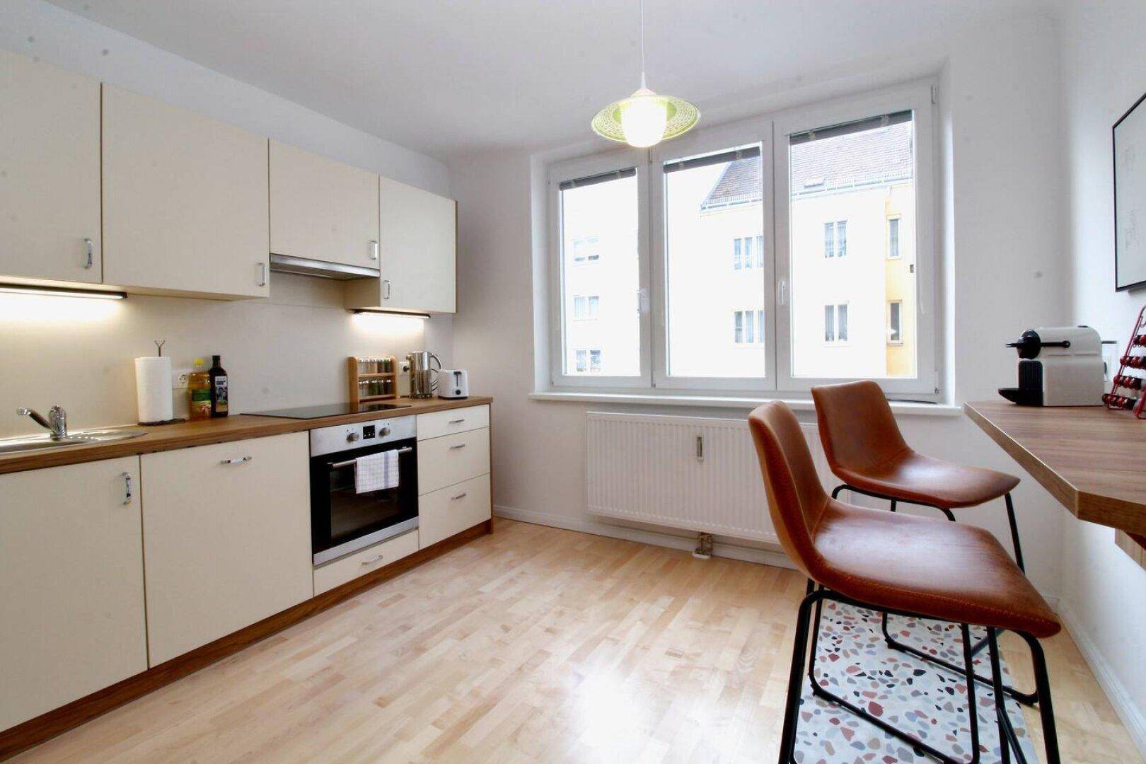 Helle Küche mit Einbauküche, Fenster und einer gemütlichen Frühstücksbar.