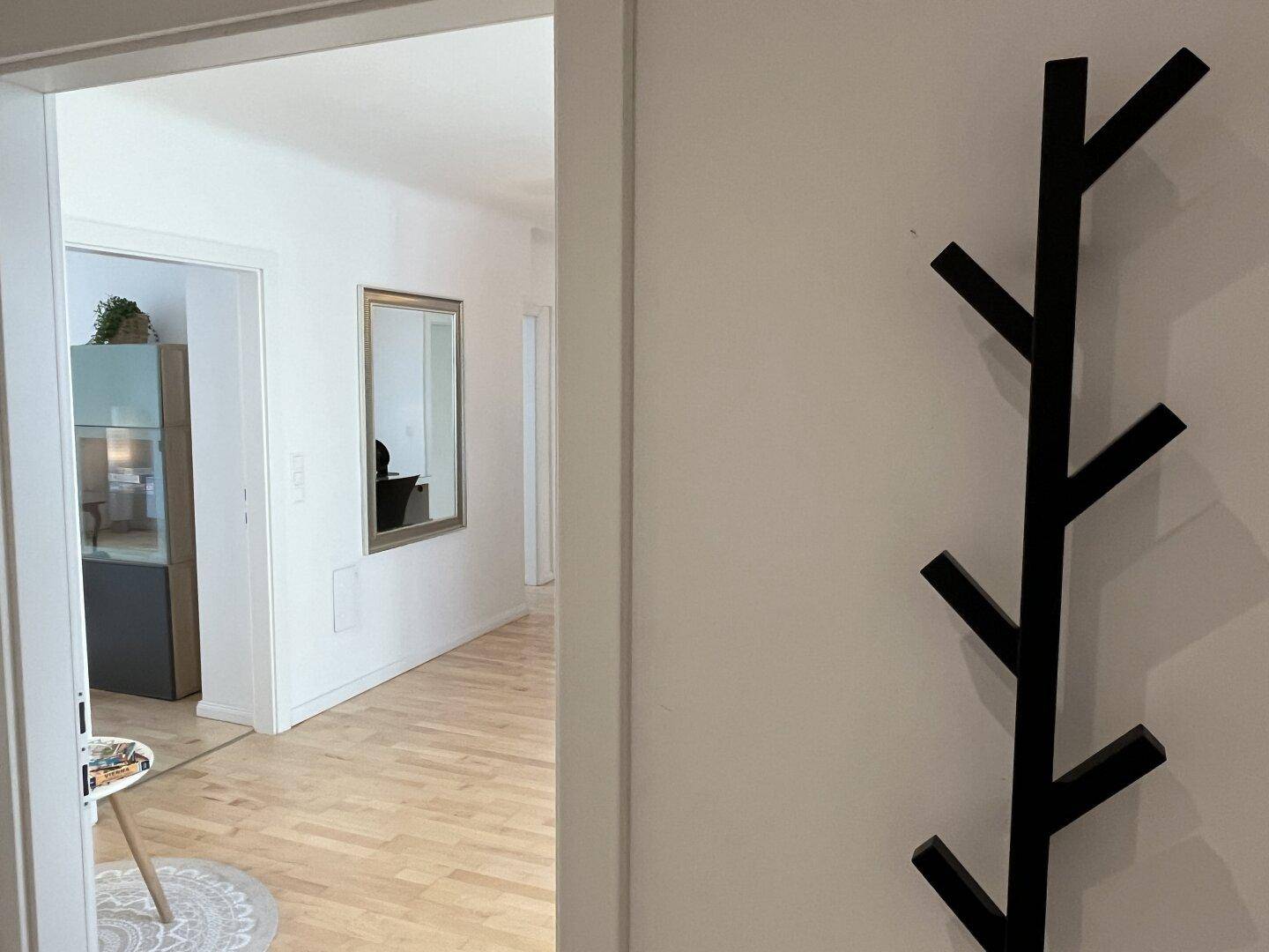 Heller Flur mit Holzboden und einem dekorativen Wandhaken.