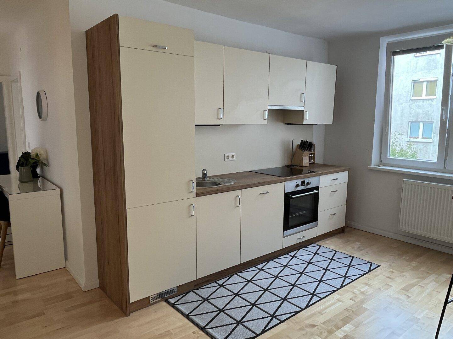 Voll ausgestattete Küche mit Einbaugeräten, Holztheke und hellem Boden.