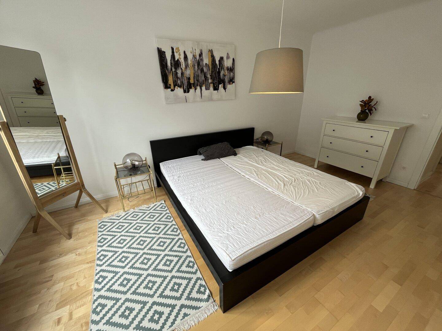 Schlafzimmer mit Doppelbett, Nachttischen und einem dekorativen Teppich.