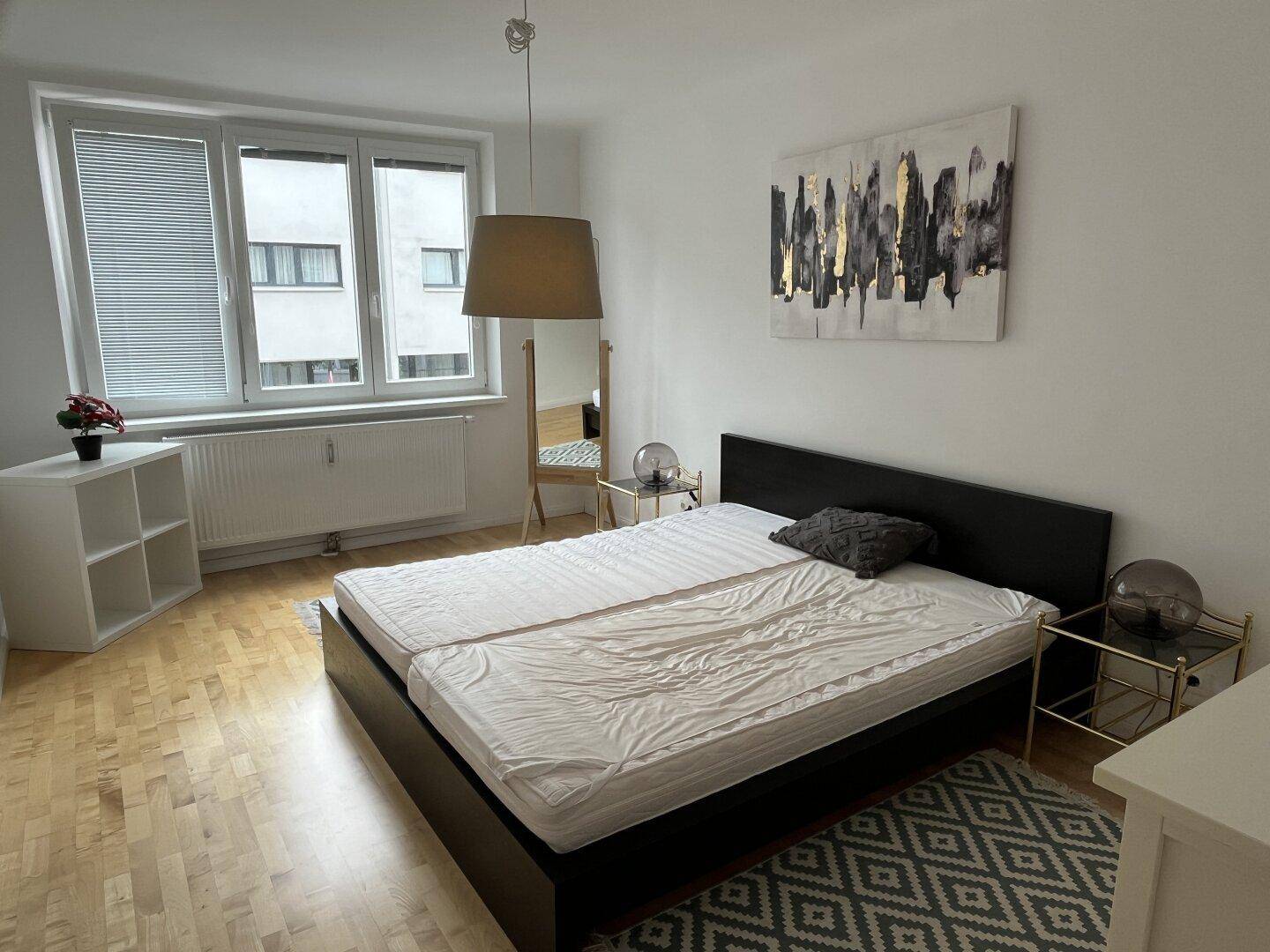 Schlafzimmer mit Doppelbett, großem Fenster und Holzboden.