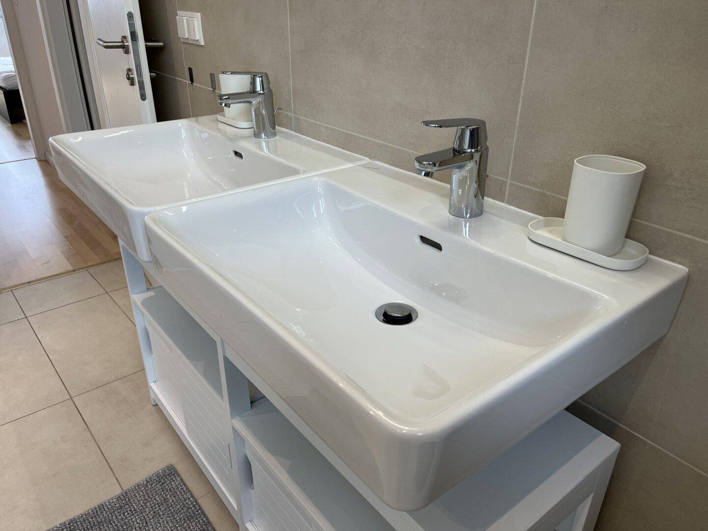 Modernes Badezimmer mit Doppelwaschbecken und hellen Fliesen.