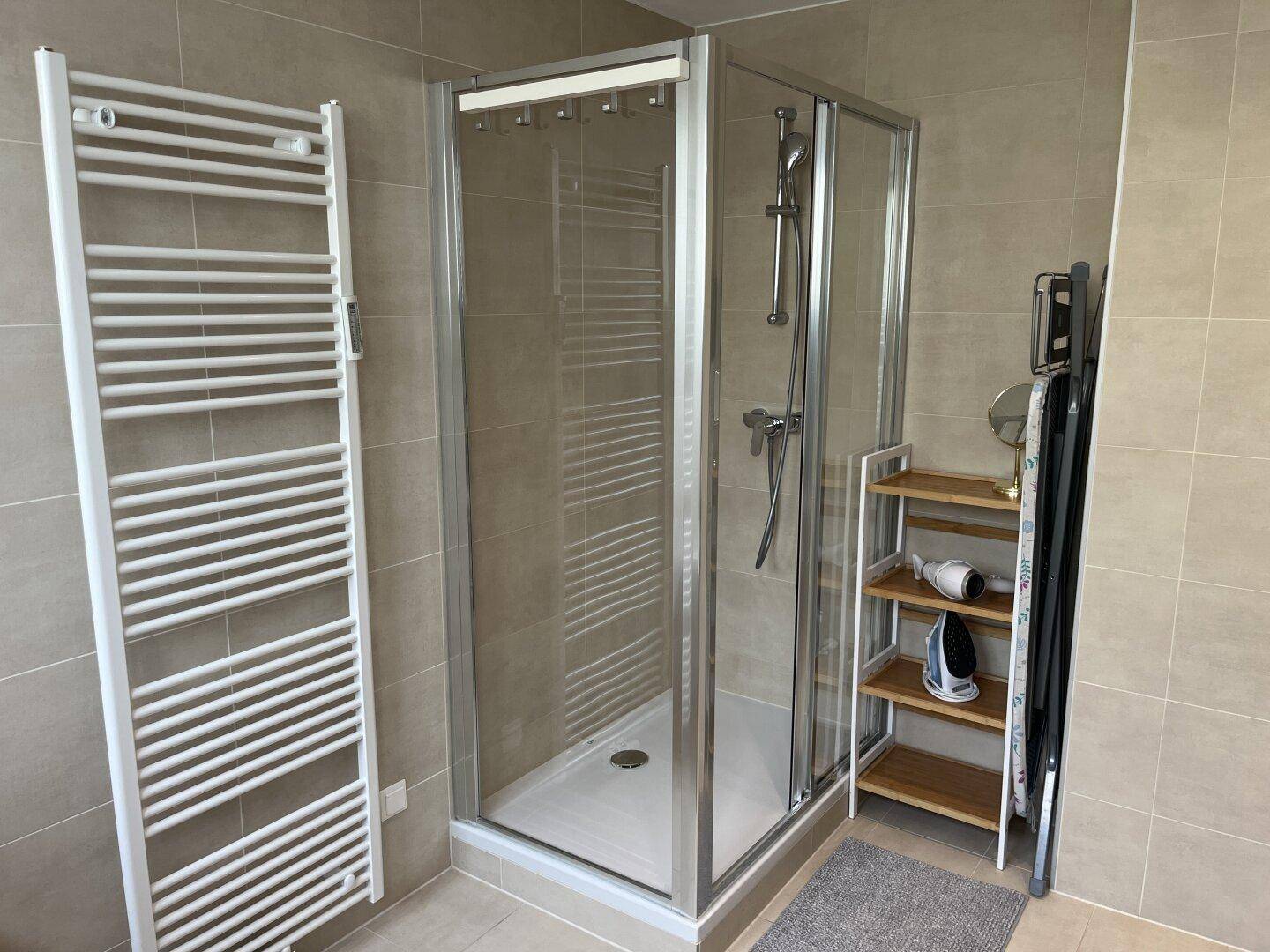 Modernes Badezimmer mit Duschkabine und beheiztem Handtuchhalter.
