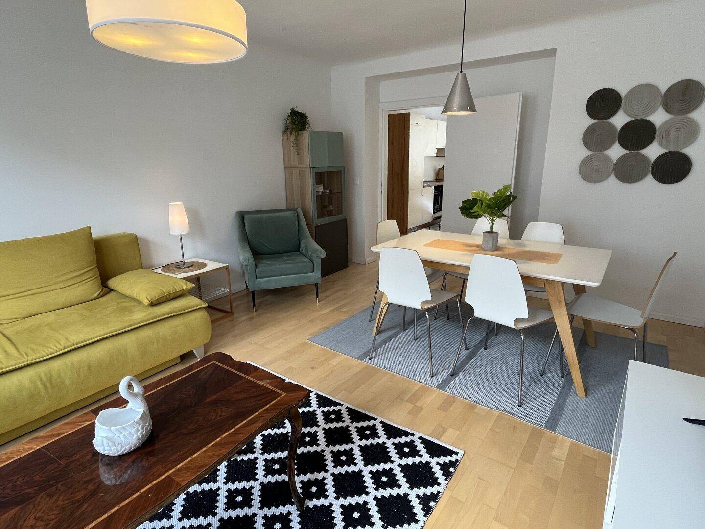 Offener Wohn- und Essbereich mit gelbem Sofa, Esstisch und hellem Holzfußboden.