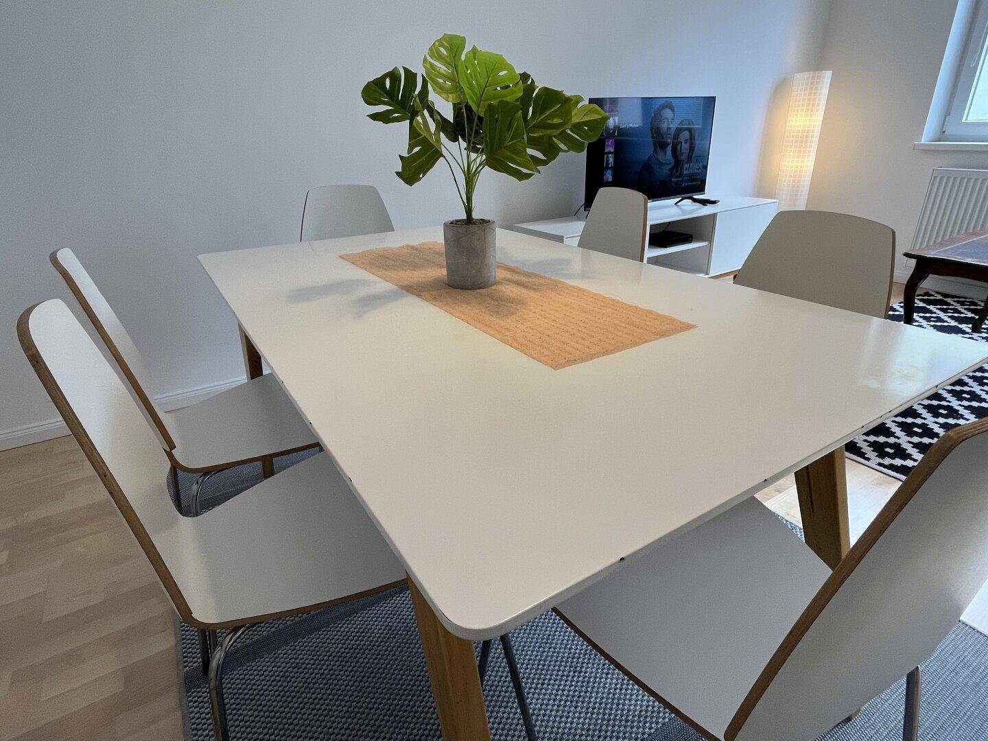 Essbereich mit modernem weißen Tisch und Stühlen, Teil des offenen Wohnbereichs.