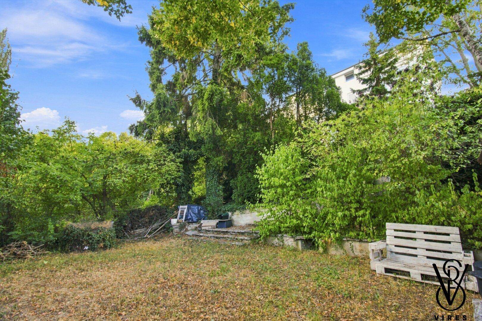 Garten mit Rasenfläche, üppiger Bepflanzung und Sitzgelegenheiten aus Paletten.