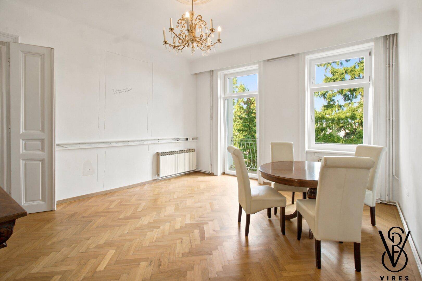 Helles Esszimmer mit klassischem Fischgrätparkett und großen Fenstern mit Blick ins Grüne.