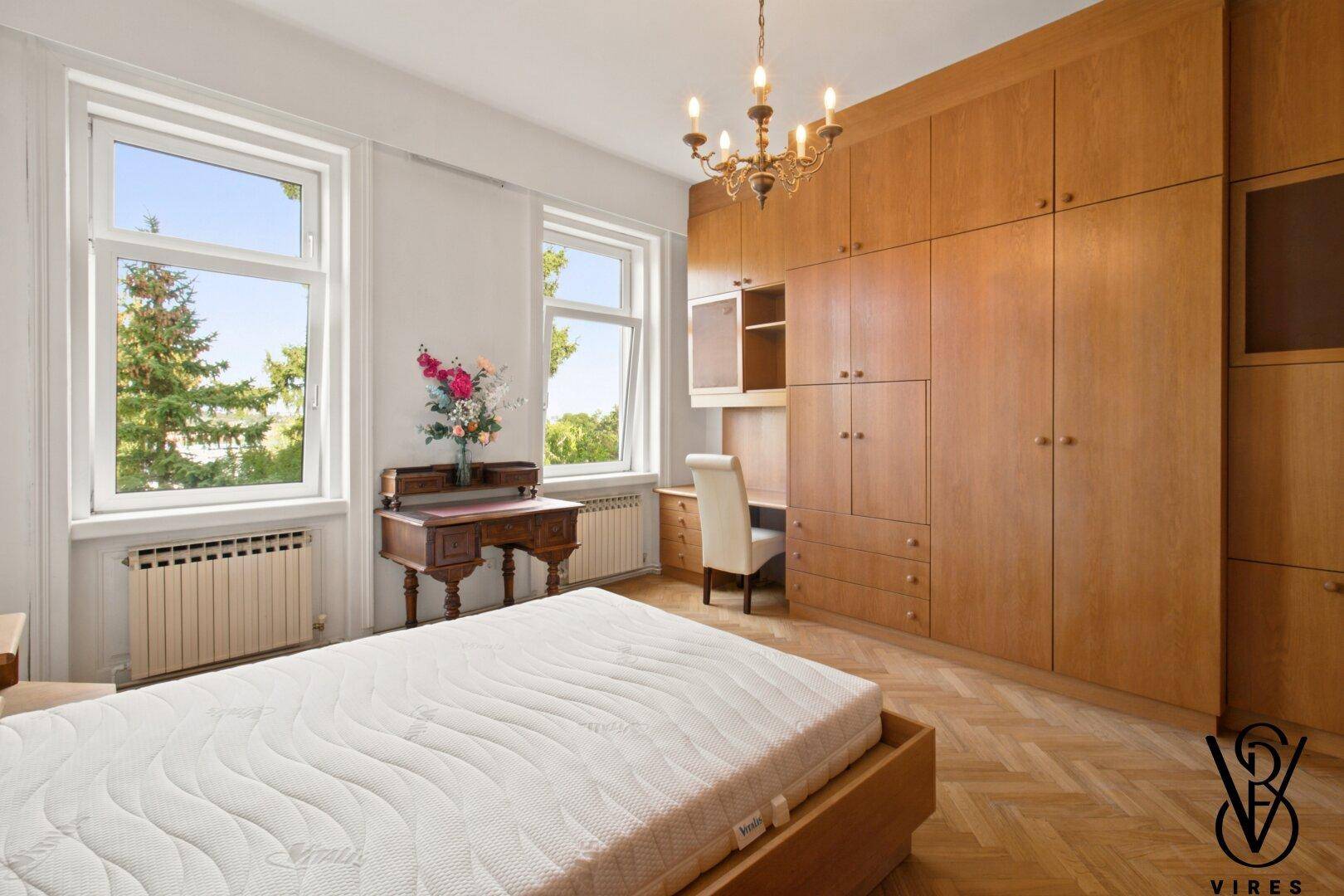 Schlafzimmer mit großem Einbauschrank aus Holz und Fischgrätparkett.