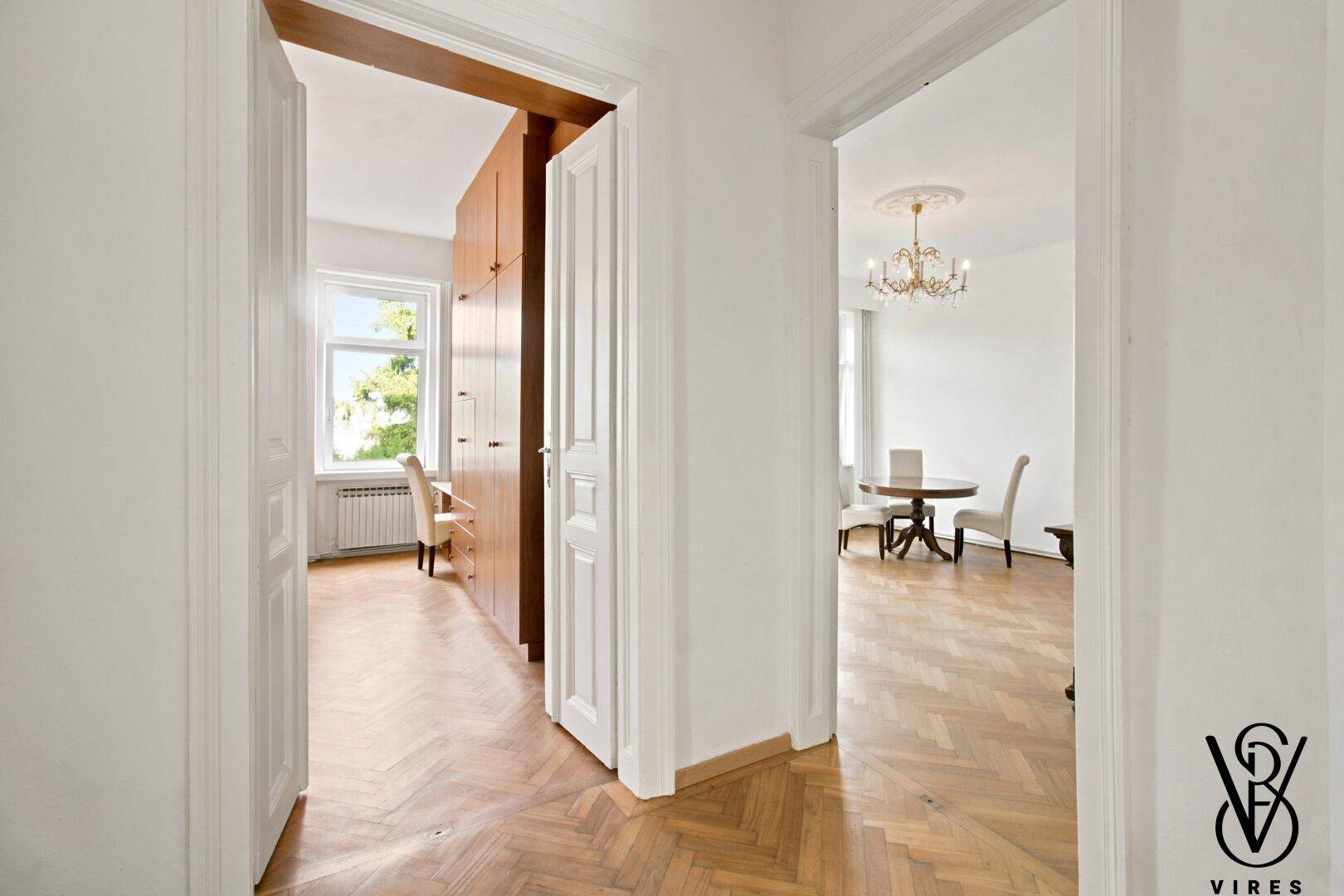 Heller Flur mit Fischgrätparkett, der den Blick in angrenzende Zimmer freigibt.