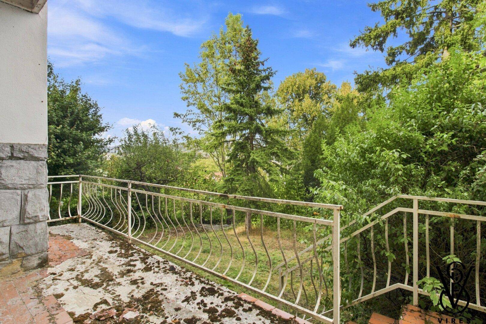 Terrasse mit Metallgeländer und Blick auf die grüne Umgebung.