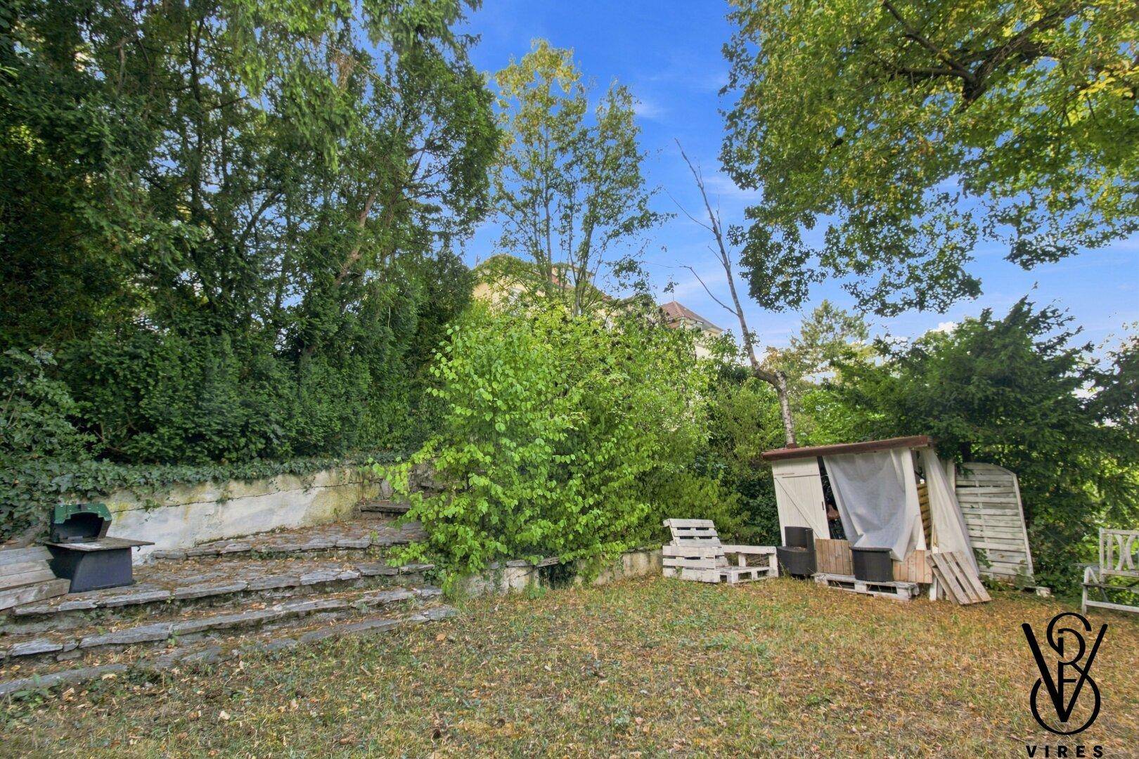 Garten mit Steintreppe, Rasenfläche und Gartenhaus.