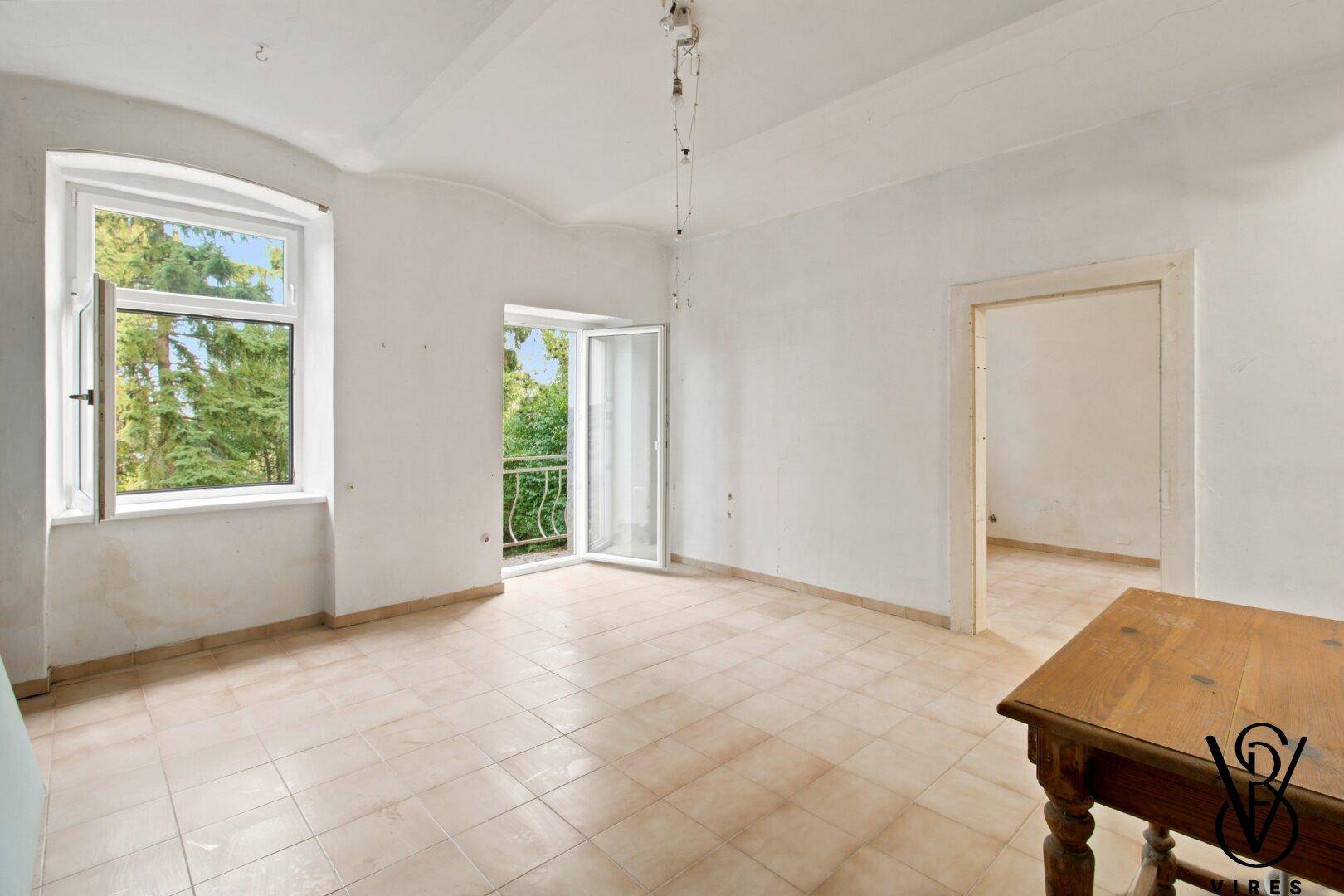 Helles Wohnzimmer mit Fliesenboden und Zugang zu einem französischen Balkon.