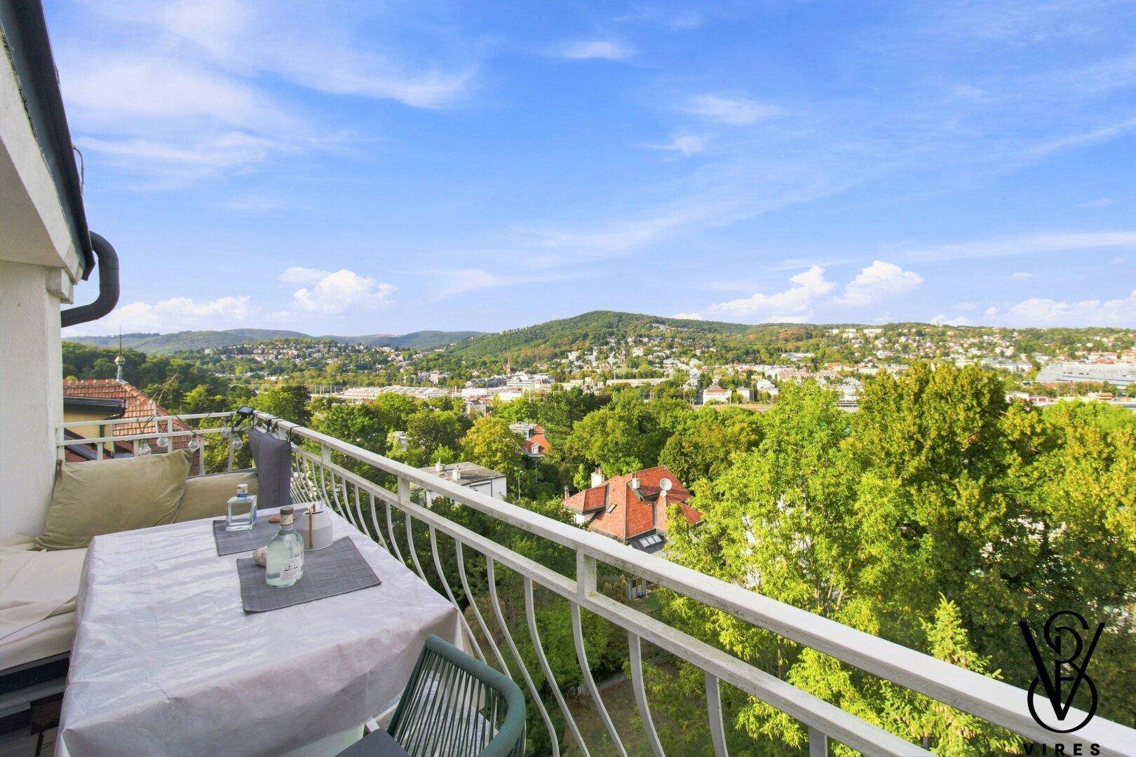 Möblierter Balkon mit Tisch und Stühlen, bietet einen weiten Blick über die grüne Umgebung.