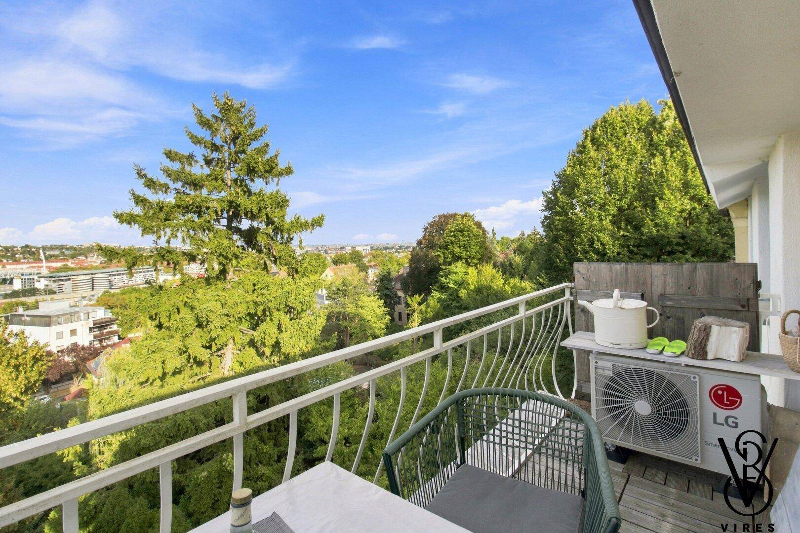 Balkon mit Klimaanlage und Blick auf die grüne Landschaft und die Stadt in der Ferne.