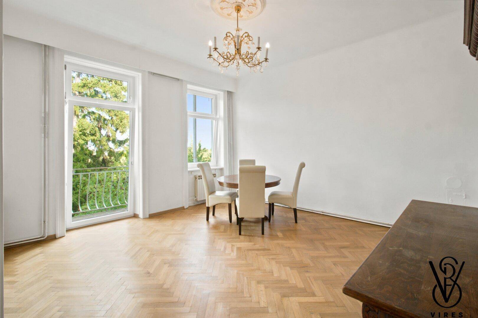 Geräumiges Esszimmer mit Fischgrätparkett, Kronleuchter und Zugang zum französischen Balkon.