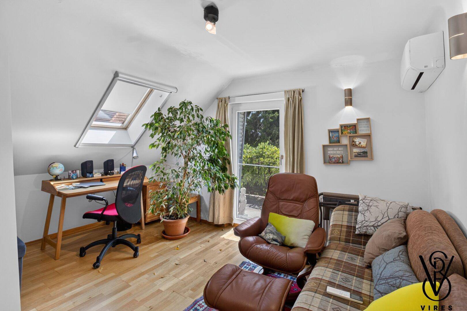 Helles Dachzimmer mit Schreibtisch, bequemer Couch und Dachfenster, ideal als Arbeits- oder Gästezimmer.
