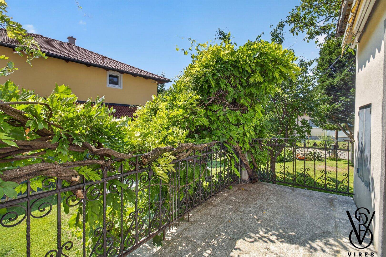 Kleiner Balkon mit schmiedeeisernem Geländer und üppiger Begrünung, ideal zum Entspannen im Freien.