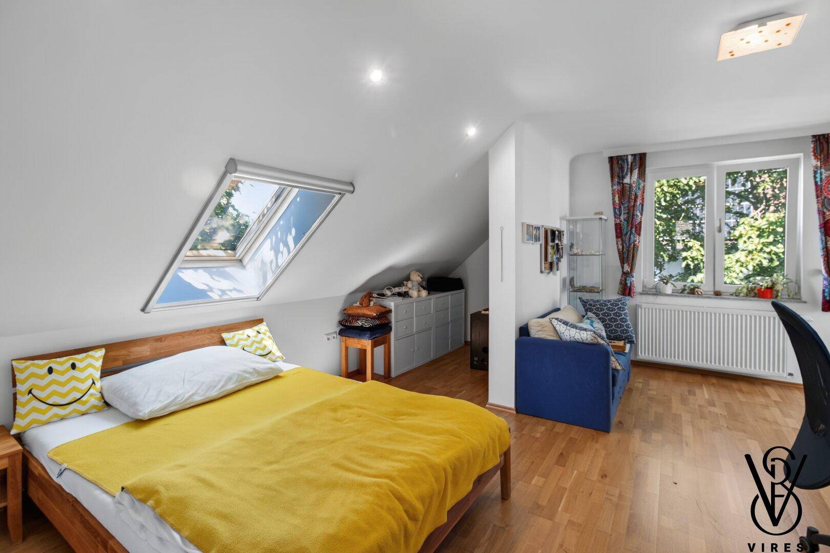 Helles Schlafzimmer mit Holzbett, Dachfenster und Blick ins Grüne, bietet eine ruhige Atmosphäre.