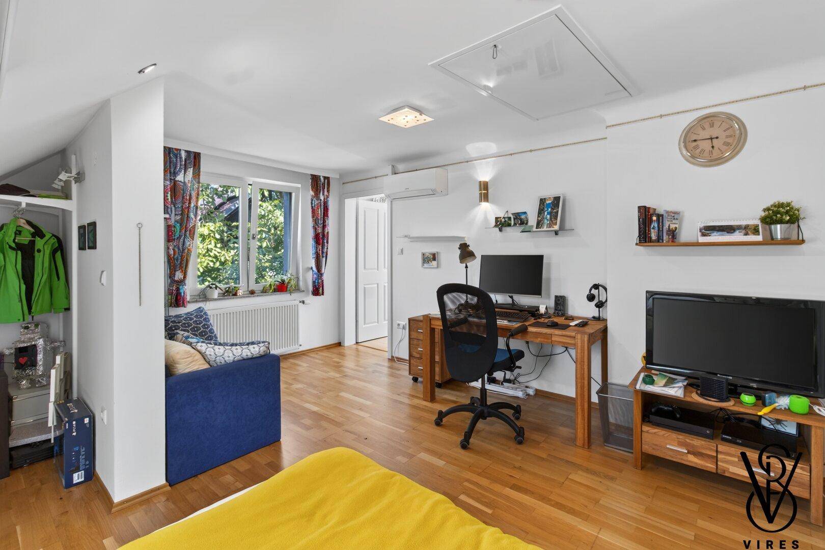 Großes Schlafzimmer mit Bett, Arbeitsbereich und Fernseher, ideal für Komfort und Funktionalität.