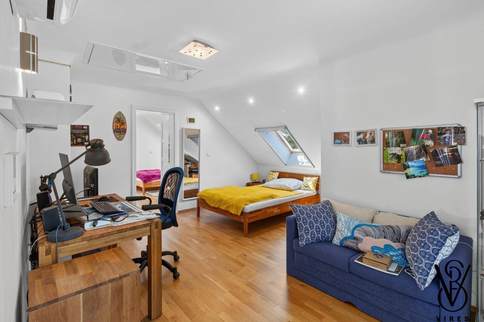Geräumiges Schlafzimmer im Dachgeschoss mit Bett, Schreibtisch und Dachfenster für viel Tageslicht.