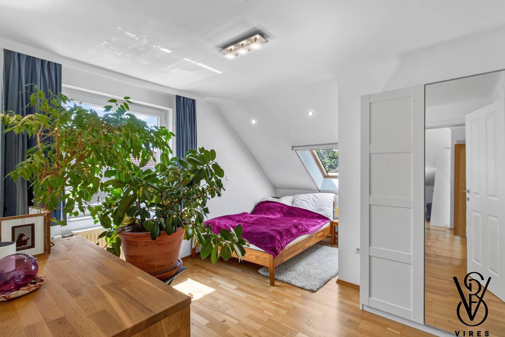 Gemütliches Schlafzimmer mit Holzbett, großem Fenster und Zimmerpflanze, schafft eine entspannte Umgebung.