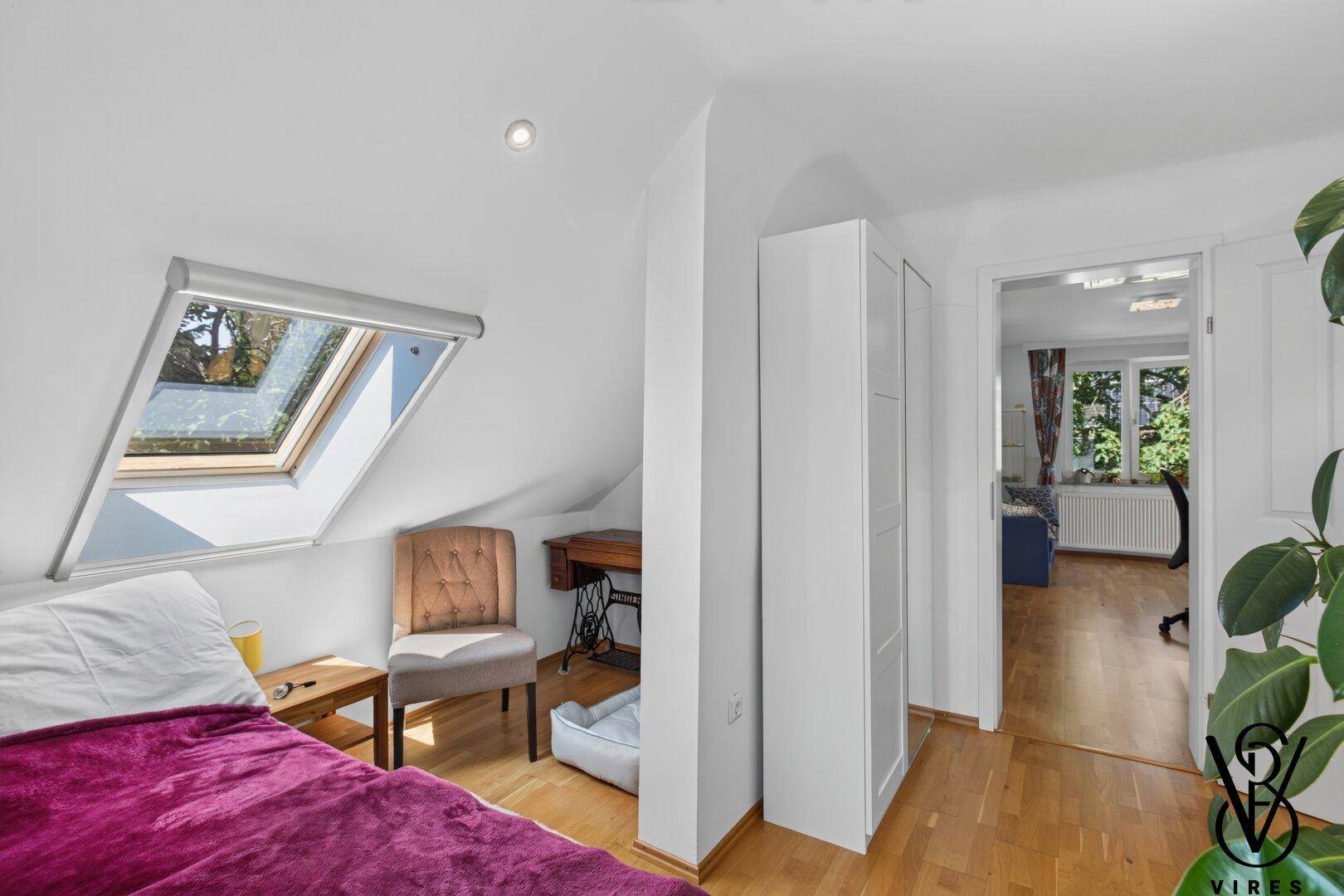 Helles Schlafzimmer mit Bett, Dachfenster und Blick ins Grüne, bietet eine ruhige Atmosphäre.
