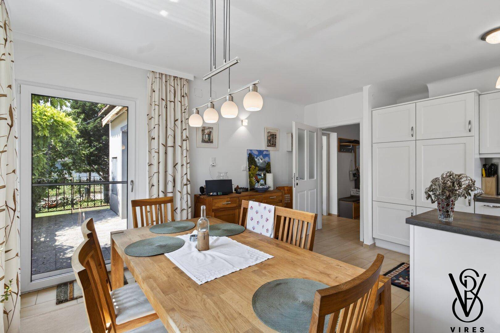 Geräumige Wohnküche mit großem Esstisch und Zugang zur Terrasse, ideal für Familienmahlzeiten.