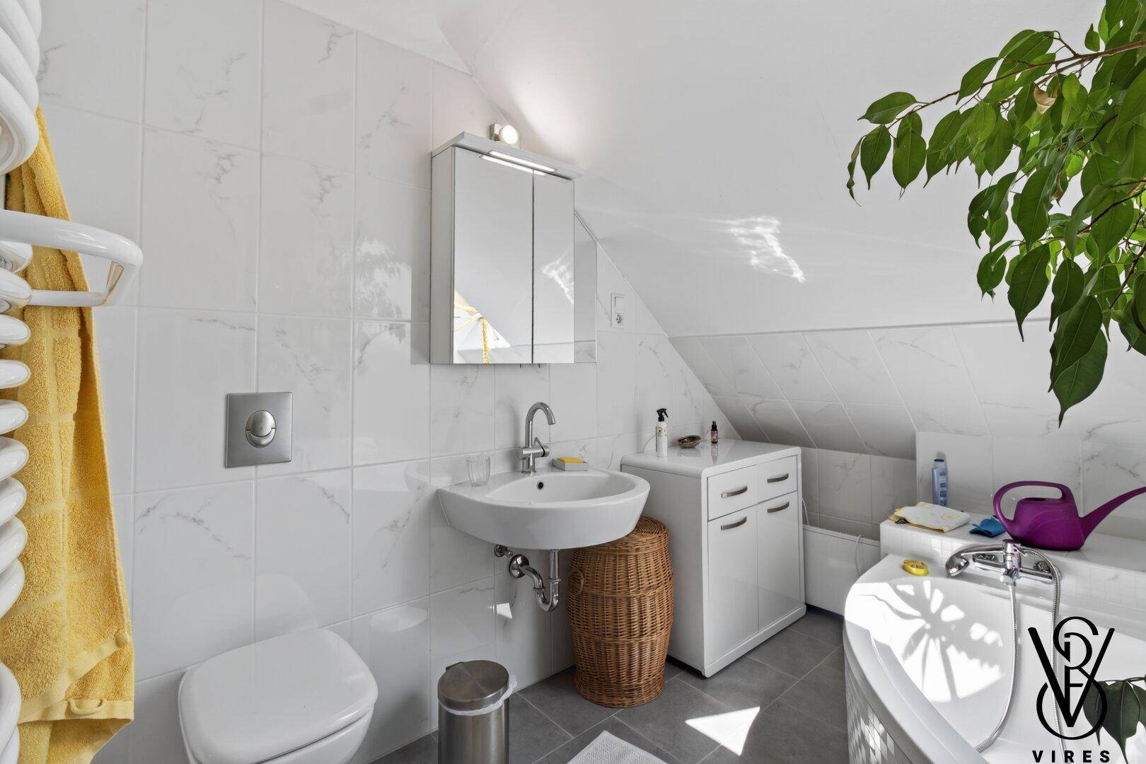 Helles Badezimmer mit Waschbecken, Toilette, Spiegelschrank und Handtuchheizkörper.