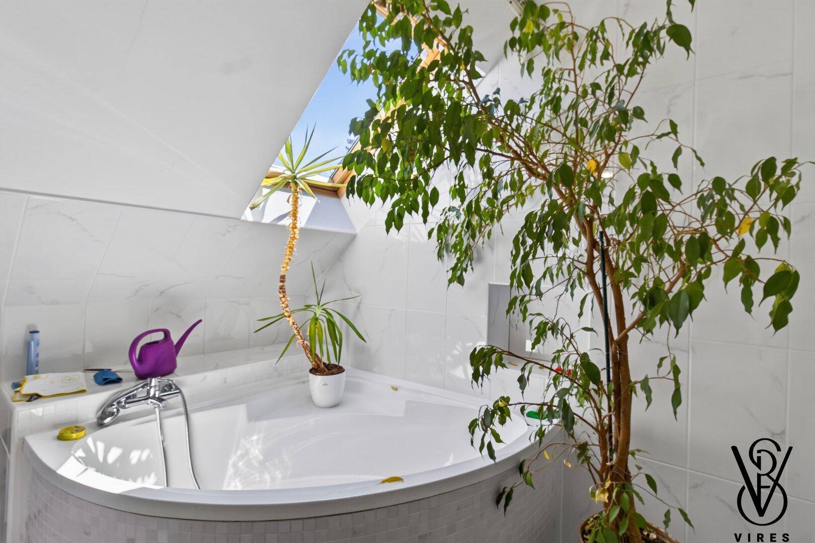 Modernes Badezimmer mit Eckbadewanne und Dachfenster, das viel natürliches Licht hereinlässt.