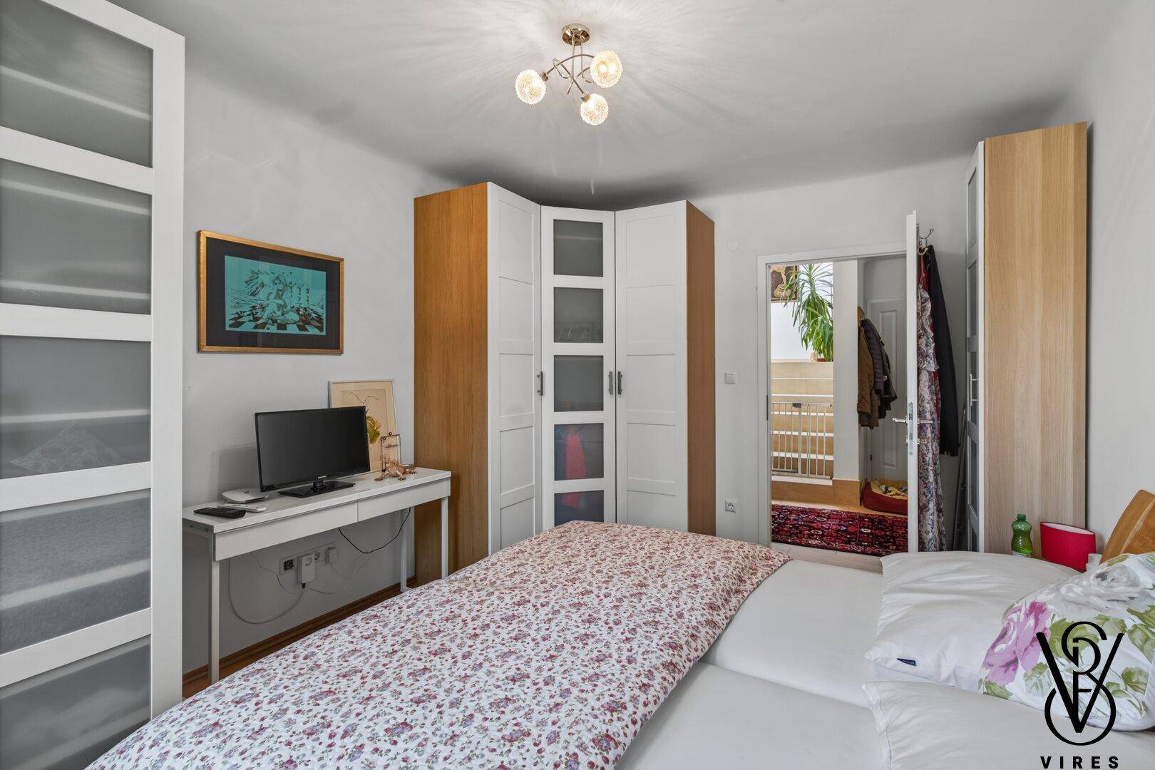 Schlafzimmer mit Doppelbett, Kleiderschränken und einem Schreibtisch.