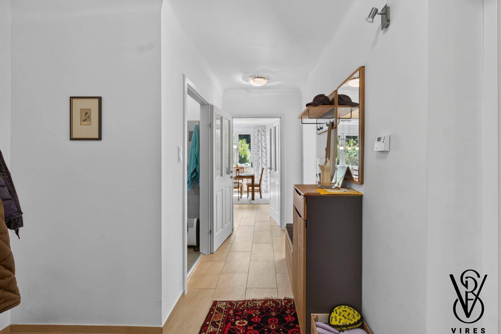 Heller Flur mit Fliesenboden, Garderobe und Durchgang zu weiteren Räumen.