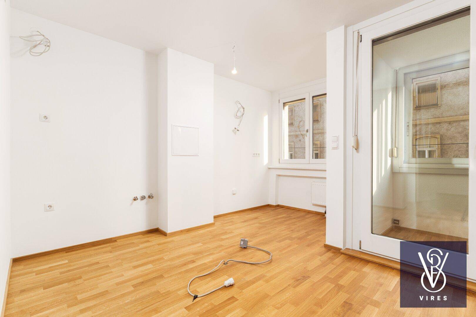 Geräumiges, helles Zimmer mit Parkettboden und Zugang zu einem kleinen Balkon oder Loggia.