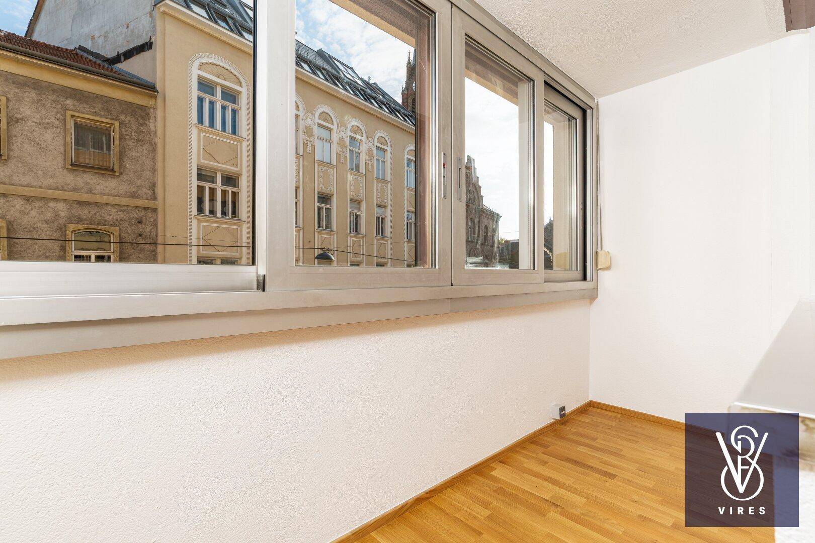 Helle Loggia mit großen Fenstern und einem weiten Blick über die städtische Umgebung.