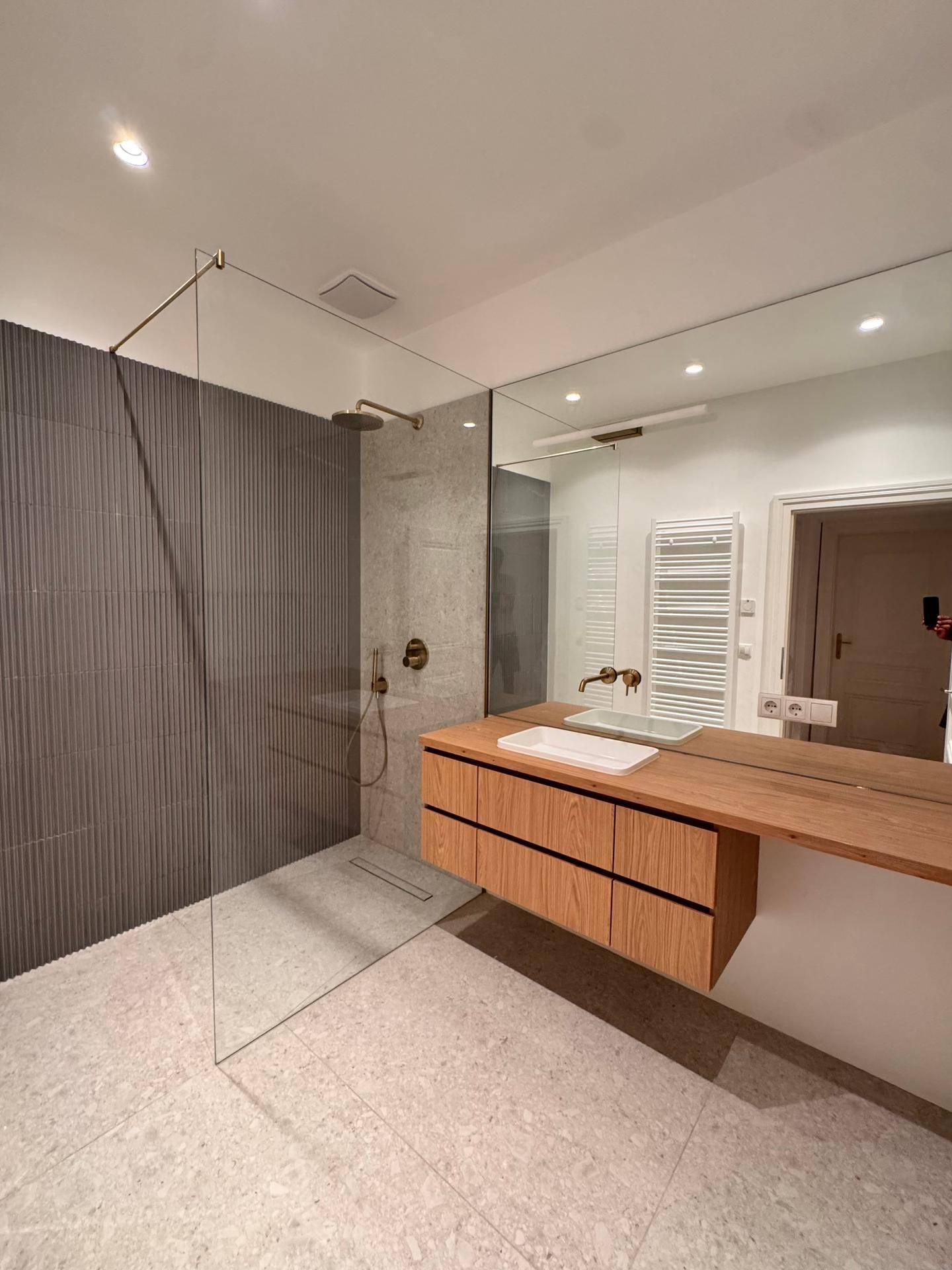 Modernes Badezimmer mit begehbarer Dusche, Holzwaschtisch und beheiztem Handtuchhalter.