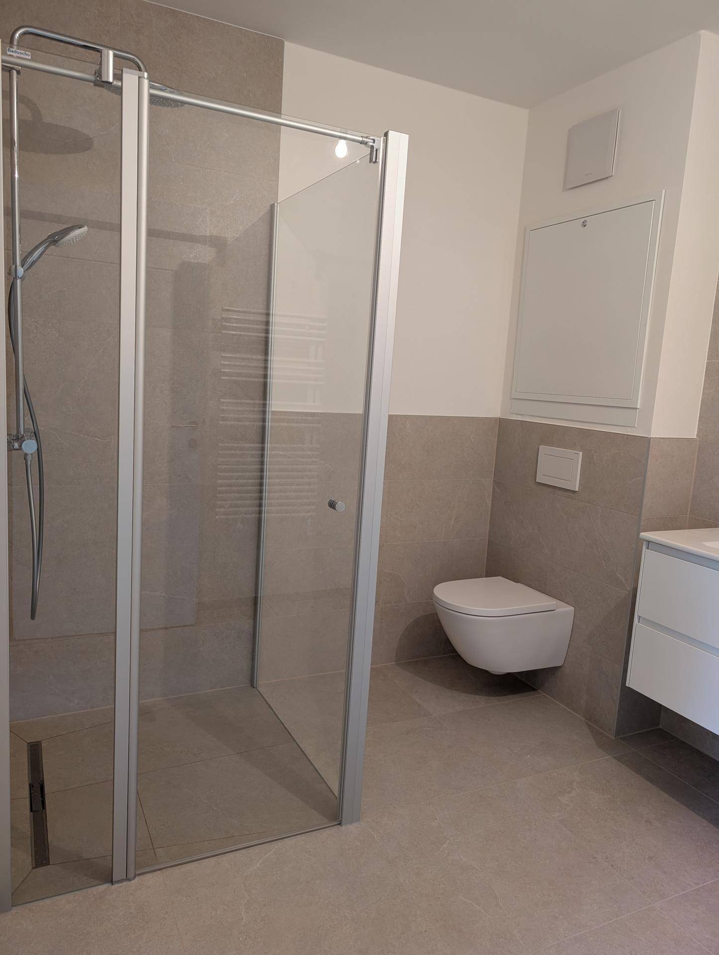 Modernes Badezimmer mit begehbarer Dusche, Wand-WC und grauen Fliesen.