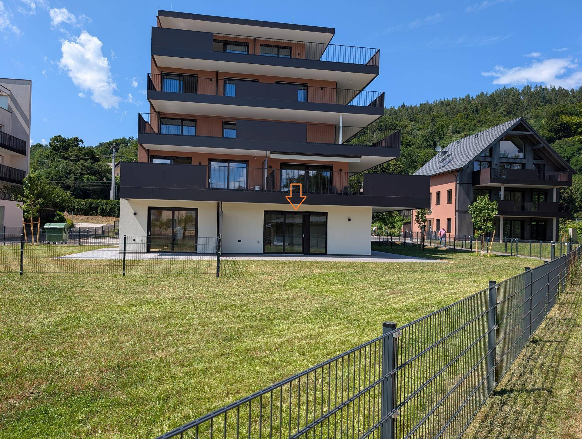 Moderne Wohnanlage mit mehreren Balkonen und einer Rasenfläche im Vordergrund.