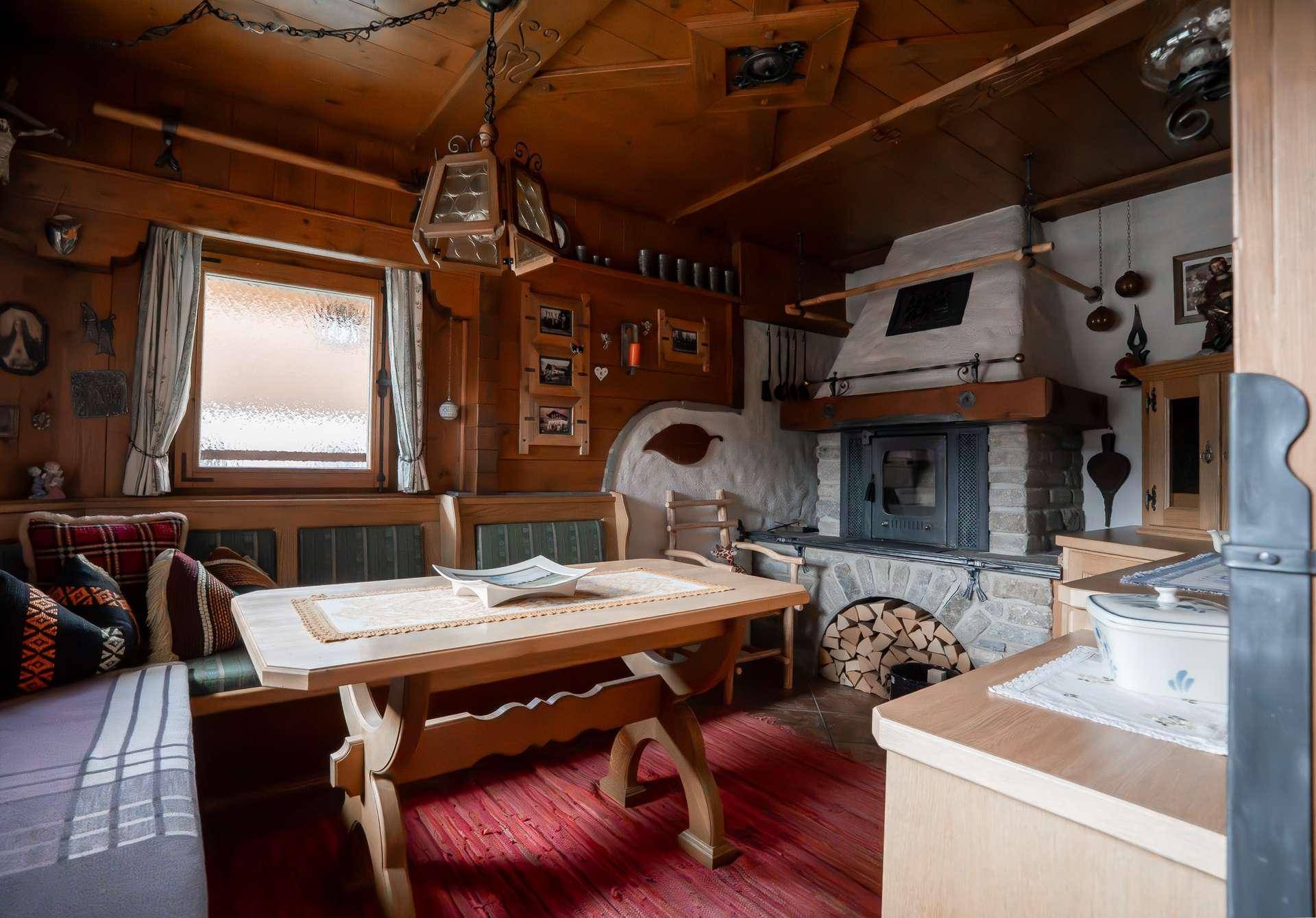 Rustikaler Wohnbereich mit Holztisch, Kamin und traditioneller Holzvertäfelung.