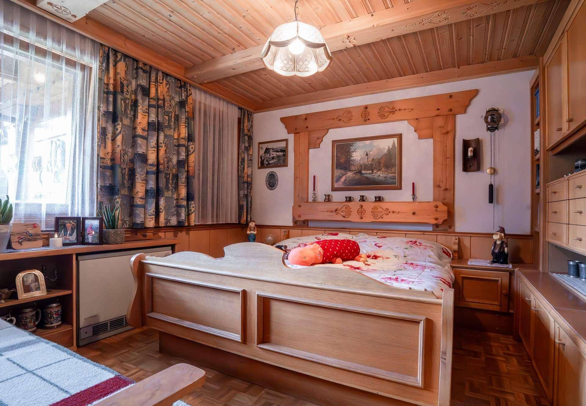 Gemütliches Schlafzimmer im alpinen Stil mit Holzvertäfelung und traditionellem Bett.